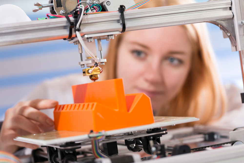 young woman 3d printing orange object